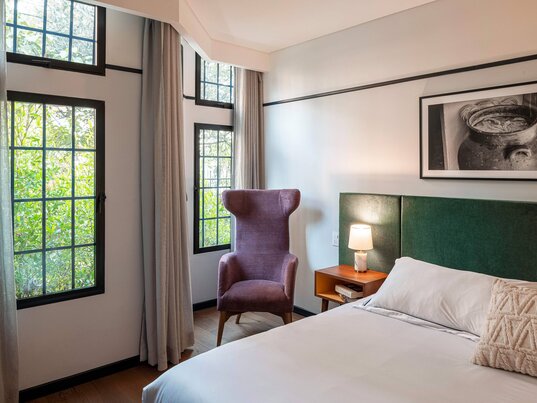 Superior Zimmer im HAB Hotel Bogotá mit modernem Design, gemütlichem Doppelbett und bodentiefem Fenster mit Vorhängen.