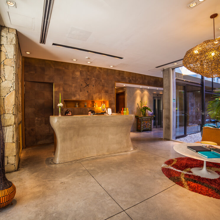 Rezeptionstresen aus Beton und Sitzecke mit Sesseln in der Lobby des Mine Hotels in Buenos Aires.