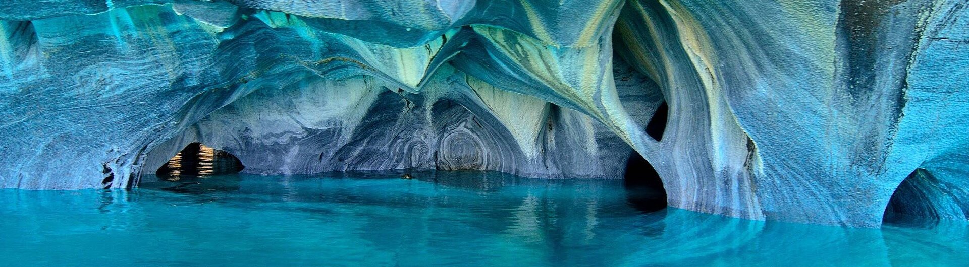 Türkisblaues Wasser und darüber blaugrün marmorierte Felsenhöhlen im Lago General Carrera in Patagonien