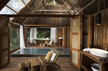 Spa-Bereich mit Indoor-Pool, Massageliege und Moebel aus Naturholz im Regenwald von Puerto Maldonado.