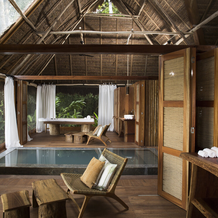 Spa-Bereich mit Indoor-Pool, Massageliege und Moebel aus Naturholz im Regenwald von Puerto Maldonado.