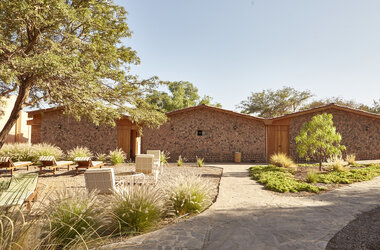 Bungalows mit Natursteinwänden und Steingarten mit Liegestuehlen im Hotel La Casa de Don Tomas, Chile.