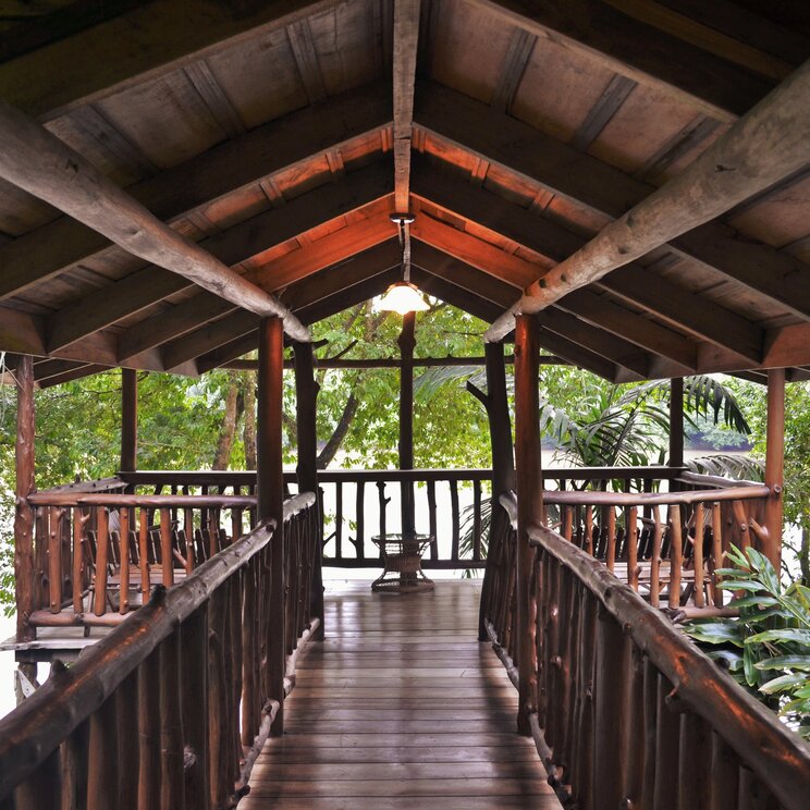 Überdachter Holzsteg und Aussichtsplattform aus Baumstämmen im Wald der Pedacito de Cielo Lodge in Boca Tapada.
