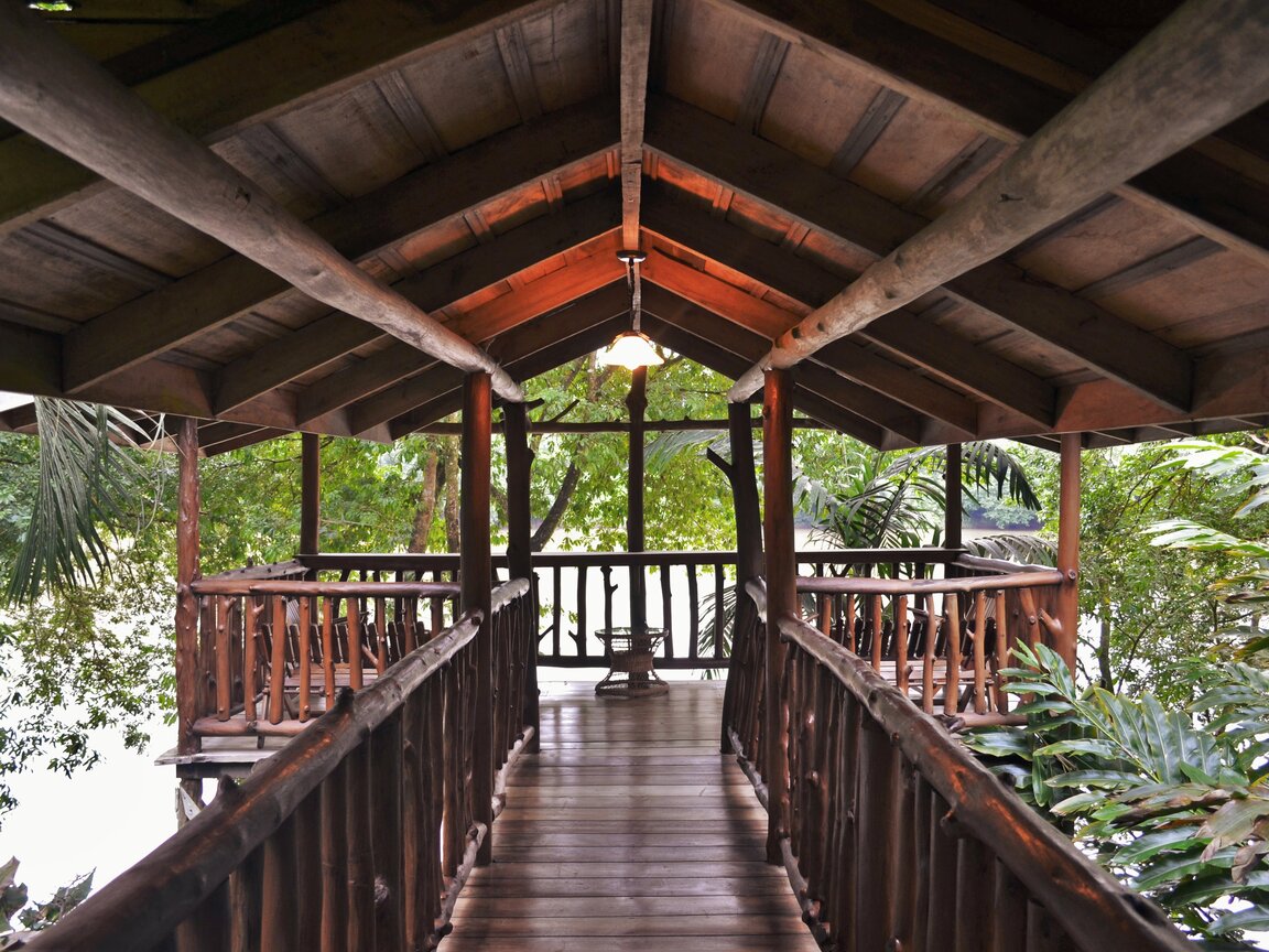 Überdachter Holzsteg und Aussichtsplattform aus Baumstämmen im Wald der Pedacito de Cielo Lodge in Boca Tapada.
