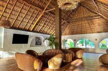 Lounge mit Korbmöbeln unter einem hohen Strohdach im Hotel Alito in Tulum, Mexiko.