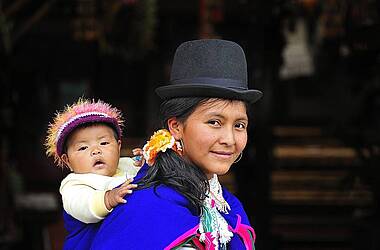 Frau in traditionell kolumbianischer Tracht mit Kleinkind auf dem Rücken
