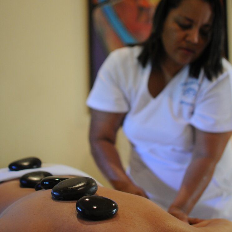 Hot-Stone-Massage-Behandlung auf dem Ruecken einer Person im Wellnessbereich des Hotels Pasatiempo