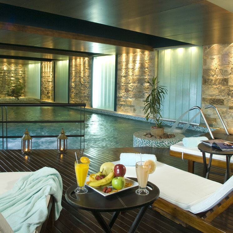 Hallenbad mit Holzdeck, Liegestühlen, Obstteller und Getränken im Imago Hotel & Spa in El Calafate, Argentinien.
