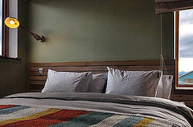 Bett mit bunt gestreifter Decke im Hotel Vendaval in Chile