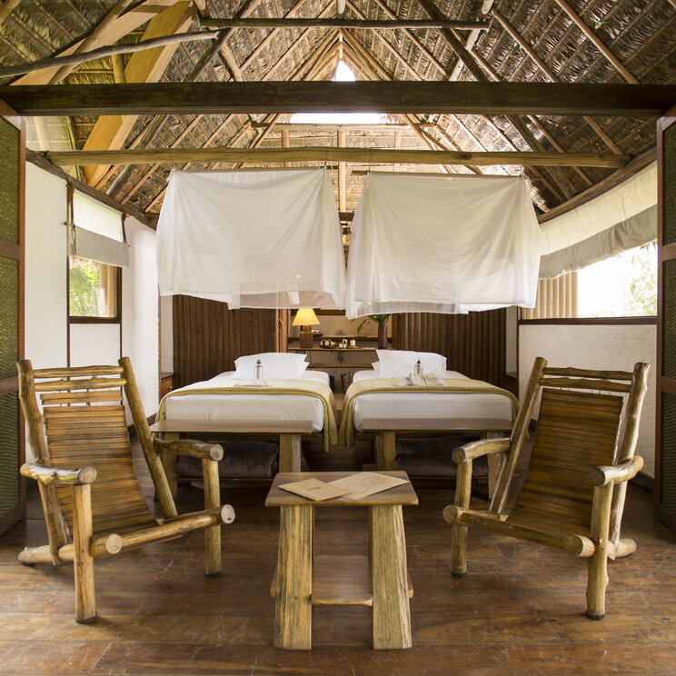 Schlafzimmer mit zwei Betten, Moskitonetzen, Holzstuehlen und Haengematten in Puerto Maldonado, Peru.