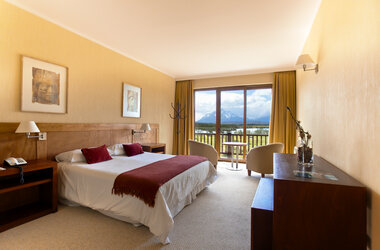 Modernes Doppelzimmer im Hotel Rio Serrano mit Blick durch große Fenster auf das Paine-Massiv in Patagonien.