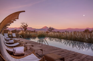 Beleuchteter Aussenpool mit Liegen zur blauen Stunde unter dem Vollmond in der Atacama-Wüste, Chile.