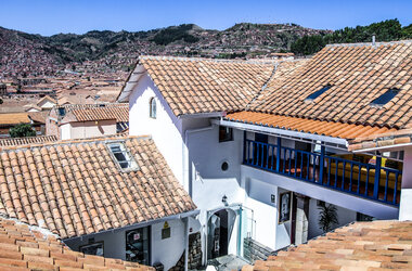 Blick auf die weissen Gebaeude und Ziegeldaecher des Hotel Tariq vor der Kulisse der Stadt Cusco.