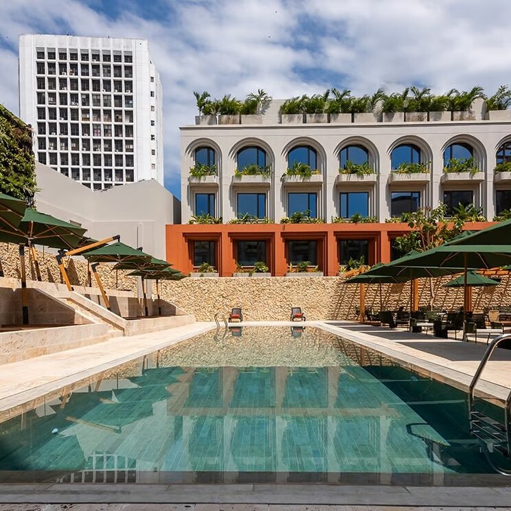Poolbereich des Osh Hotel in Cartagena, Kolumbien, mit eleganter Architektur, Sonnenschirmen und modernen Sitzgelegenheiten.
