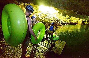 Drei Personen tragen ihre Schwimmreifen und bereiten sich darauf vor Cave Tubing zu machen
