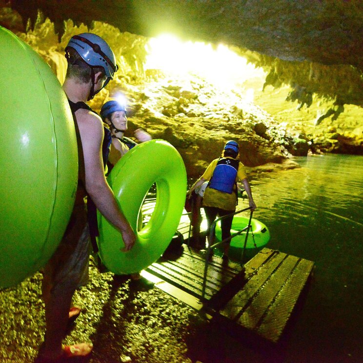 Drei Personen tragen ihre Schwimmreifen und bereiten sich darauf vor Cave Tubing zu machen