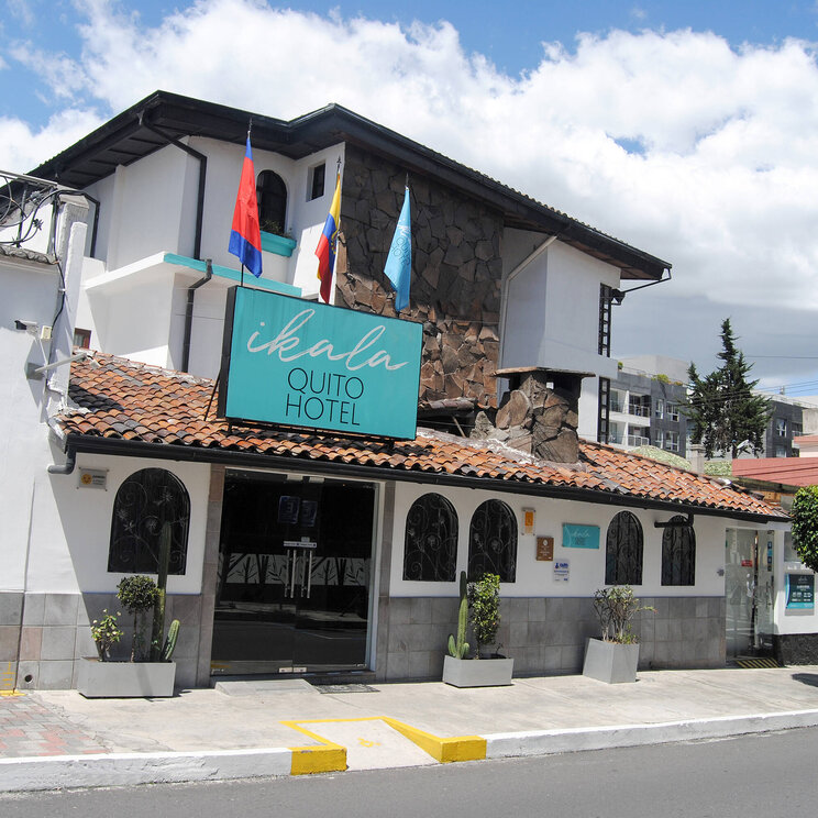 Außenansicht des Ikala Quito Hotel in Ecuador mit traditioneller Fassade, Flaggen und zentraler Lage in der Stadt.