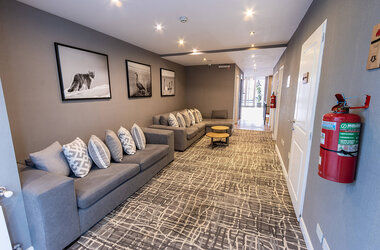 Loungebereich im Hotel Alto Andino in Ushuaia, Argentinien, mit modernen Sofas, dekorativen Schwarz-Weiß-Fotografien und stilvollem Teppichdesign im Flur.
