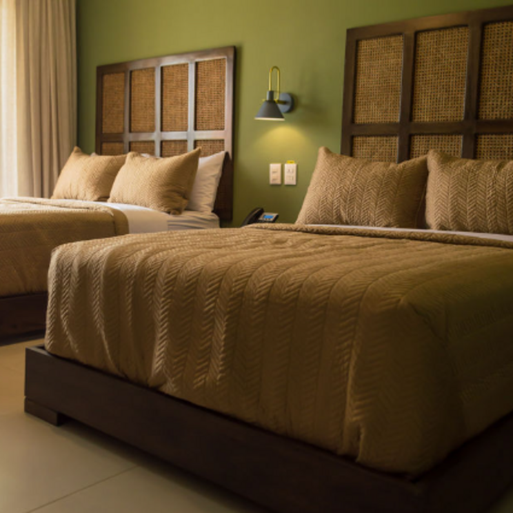 Zimmer im Hotel Pinar Dorado in Jarabacoa, Dominikanische Republik, mit zwei Doppelbetten, schlichter Einrichtung und warmen Naturtönen für eine gemütliche Atmosphäre.