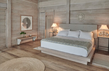 Schlafzimmer mit Holzwänden und -boden, Kingsize-Bett und Dekoration in Mancora, Peru.