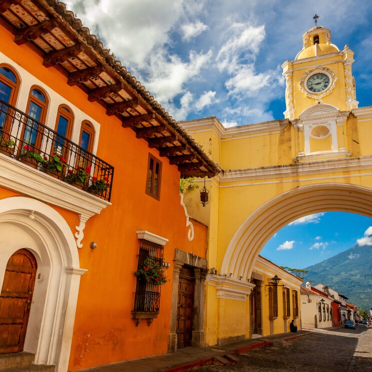 Der gelbe Santa-Catalina-Bogen mit Uhrturm in Antigua Guatemala, vor der Kulisse des Vulkans Agua.