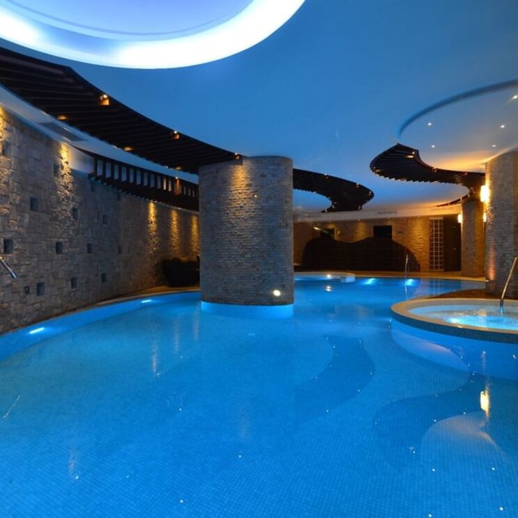 Beleuchteter Innenpool im Camino Real Hotel Santa Cruz mit Steinsaeulen und blauer Unterwasserbeleuchtung.