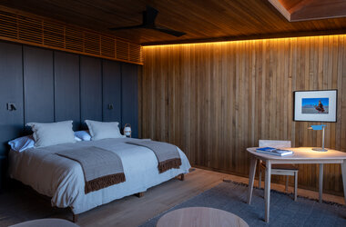 Schlafzimmer mit Doppelzimmer, Holzwand und Schreibtisch im Hotel in Chile.