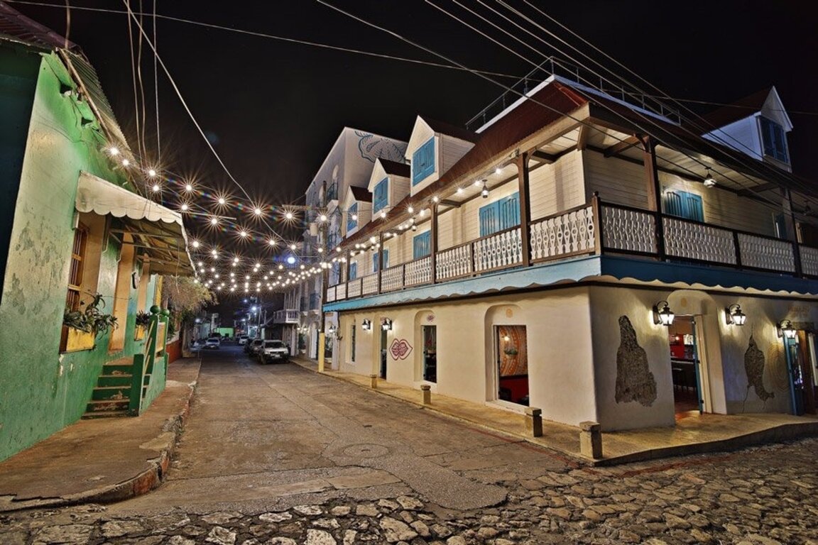 Hotel Isla de Flores bei Nacht, beleuchtete Gasse mit Lichterketten und kolonialen Balkonen in Flores, Guatemala.