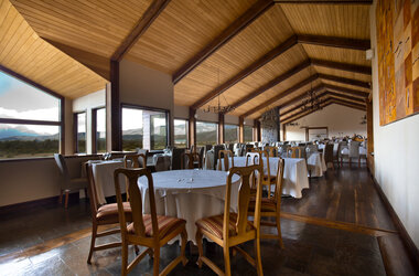 Innenansicht der Lobby im Hotel Rio Serrano mit hohen Decken, Holzverkleidung und Blick auf die Berge Chiles.