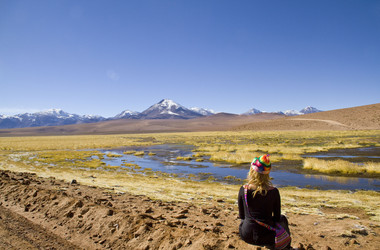 Frau sitzt in der Atacamawüste und betrachtet die Landschaft