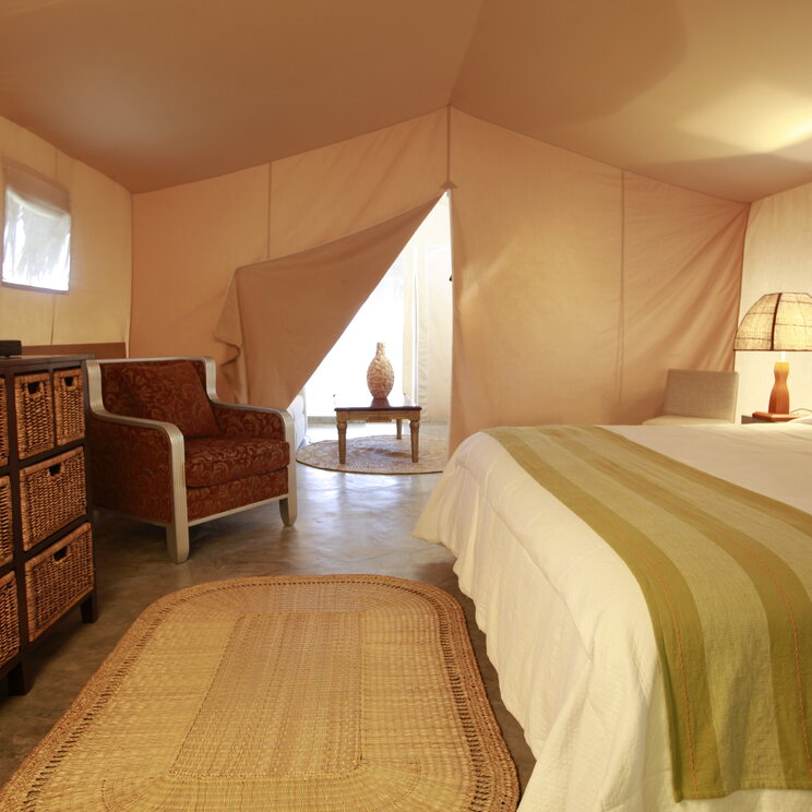Aranwa: Blick in ein komfortables Glamping-Zelt mit Bett, Sessel, Fernseher und Meerblick.
