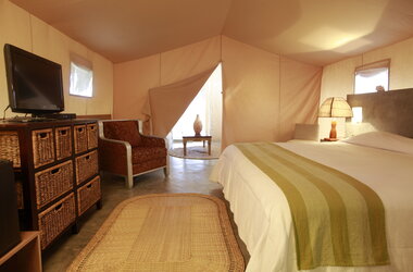 Aranwa: Blick in ein komfortables Glamping-Zelt mit Bett, Sessel, Fernseher und Meerblick.