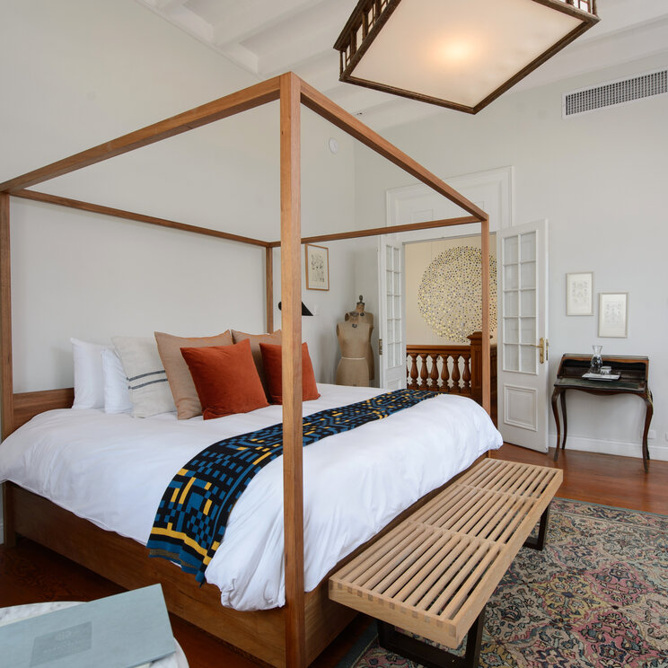 Suite mit Himmelbett, Kissen, Holzboden, Teppich und Blick ins Badezimmer im Hotel Villa Barranco in Lima, Peru.