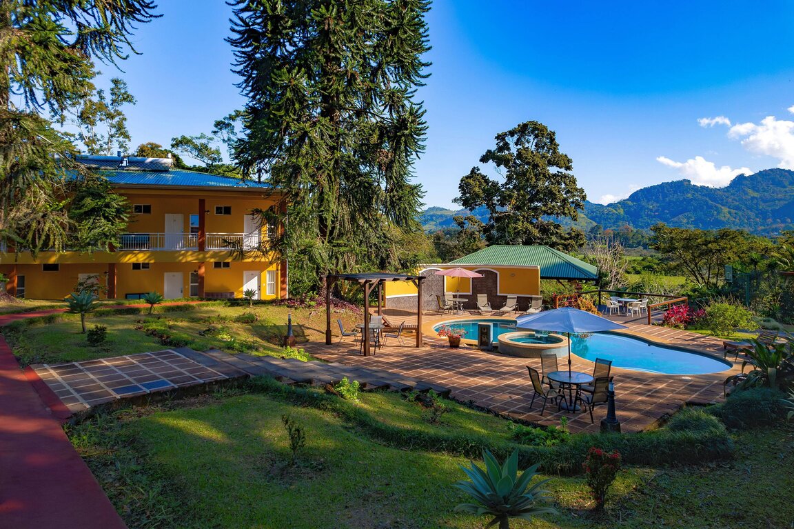 Außenansicht des Hotel Villa Florencia in Costa Rica mit Garten, Poolbereich und Blick auf die umliegenden Berge.