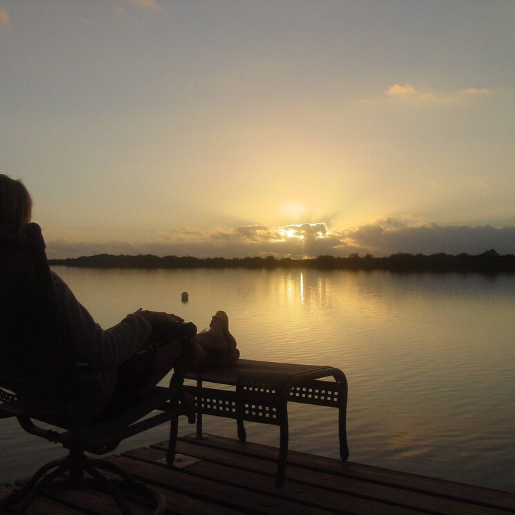 Gast entspannt am See mit Sonnenuntergang in der Lamanai Outpost Lodge, Belize.