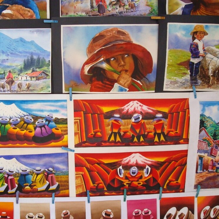 Bunte Gemälde mit Andenmotiven und indigenen Szenen an einem Marktstand in Ecuador.