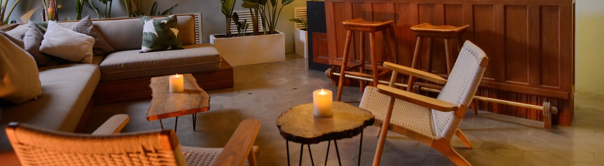 Beleuchtete Terrasse mit Holzbar, Sesseln, Sofa, Kissen, Kerzen und Pflanzen im Hotel Villa Barranco in Lima, Peru.