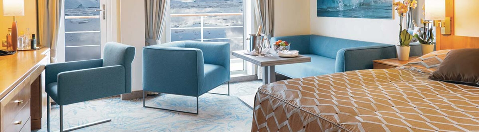 Suite an Bord der Ocean Seaventure Antarktis Expeditionskreuzfahrt mit Wohnbereich, großem Bett, Balkon und Panoramablick auf Eisberge und Meer.