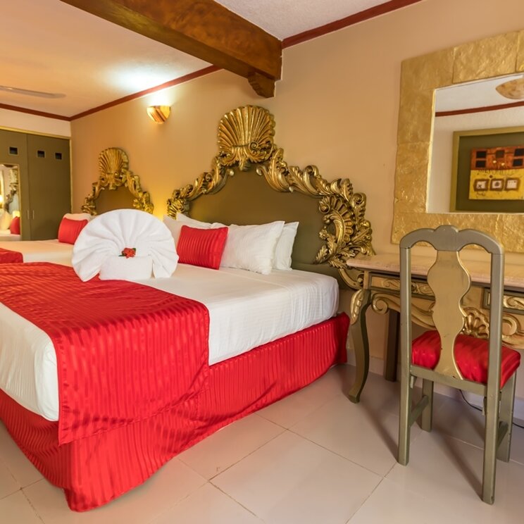 Zimmer im Hotel Las Golondrinas in Playa del Carmen mit zwei Betten, dekorativen Kopfteilen und Schreibtisch.
