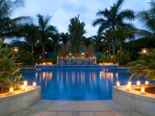 Der beleuchtete Pool des Hotels Alma del Pacífico am Playa Esterillos Este in Costa Rica, umgeben von Palmen.