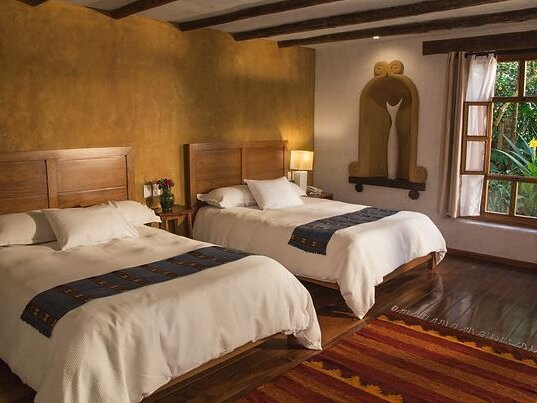 Suite mit Kamin, Kronleuchter, dunklen Deckenbalken und bunter Fensterfront im Guayaba Inn, San Cristobal.