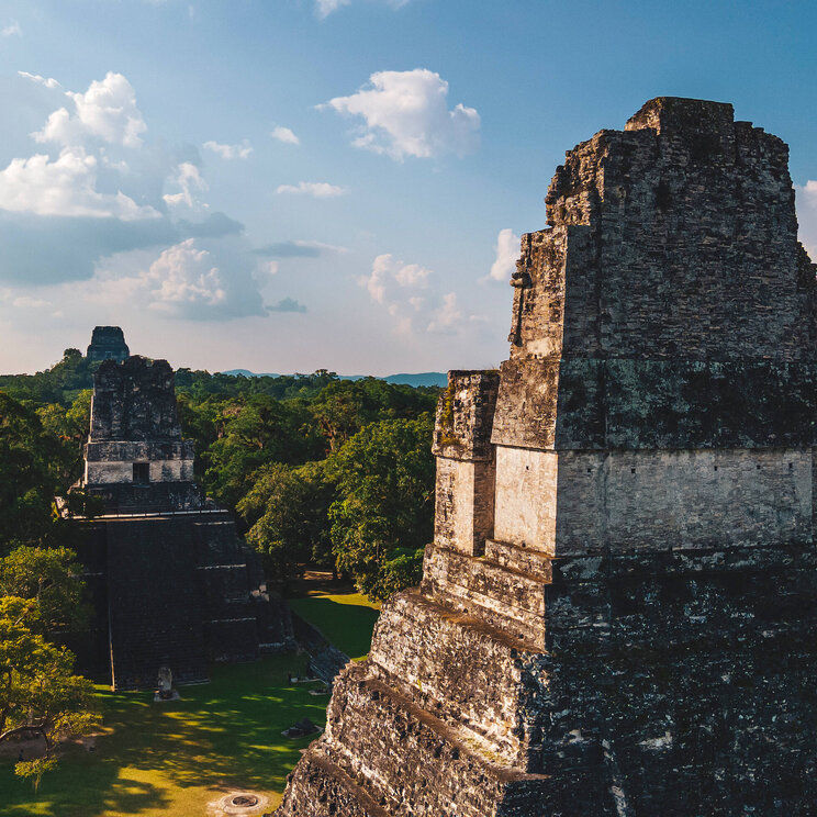 Blick auf die antiken Mayaruinen von Tikal im Regenwald von Petén, Guatemala, mit imposanten Tempeln, die aus dem dichten Grün herausragen.