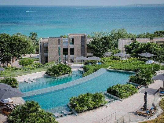Weitläufiger Infinity-Pool im Sofitel Barú Calablanca Resort mit Blick auf das türkisblaue Karibische Meer und moderne Architektur inmitten tropischer Vegetation.