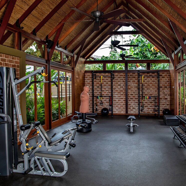 Fitnessraum im Hotel Amor Arenal in La Fortuna, Costa Rica, mit modernen Geräten, offener Holzkonstruktion und Blick ins tropische Grün.