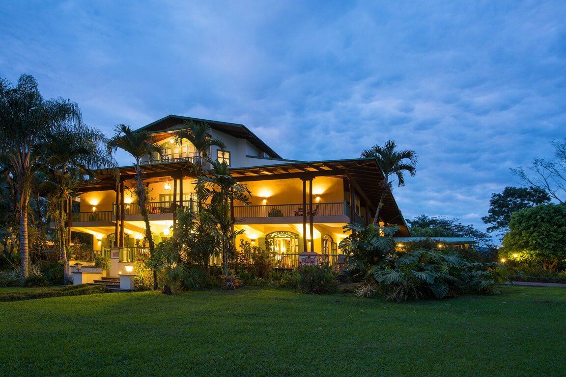 Hotel Casa Turire bei Turrialba, Costa Rica, stimmungsvoll beleuchtet am Abend, umgeben von tropischem Garten und kolonialer Architektur mit großzügiger Veranda.