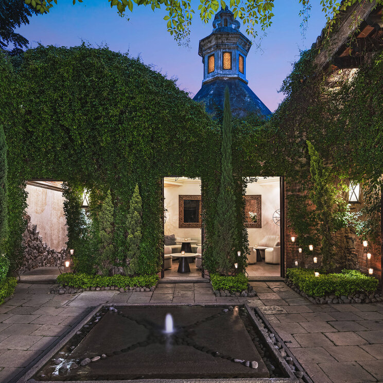 Begrünter Innenhof mit Brunnen und Blick auf den Eingang des El Convento Boutique Hotels in Antigua, Guatemala – stilvolle Kolonialarchitektur mit romantischem Flair in zentraler Lage.