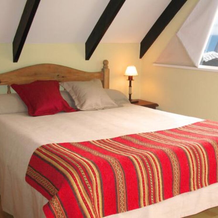 Bett mit rotem Überwurf im Hotel La Aldea