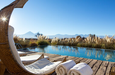 Liegestuhl am Pool mit Blick auf die Atacama-Wüste und Vulkane in Chile.