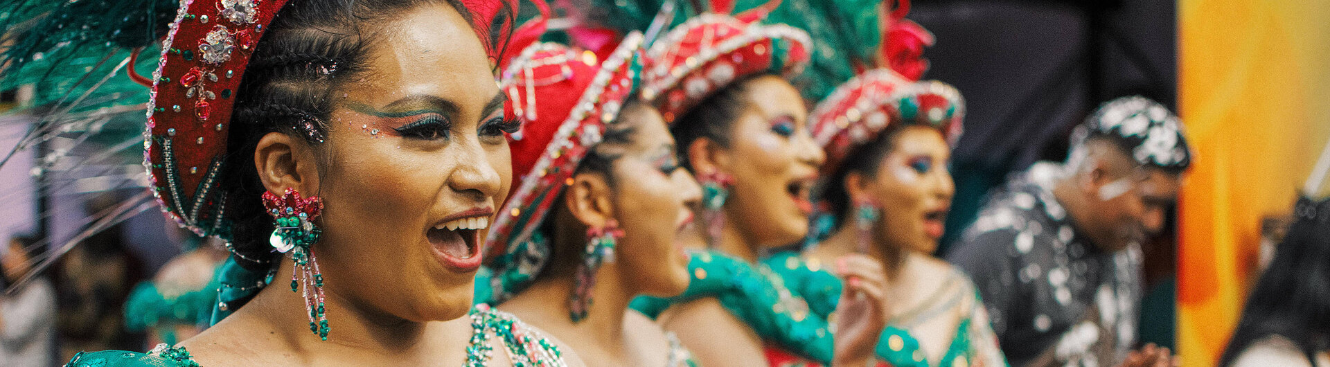 Tänzerinnen beim Karneval in Oruro. Sie tragen grünrote Kostüme und rote Hüte mit einer grünen Feder