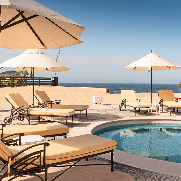 Pool mit Liegen und Sonnenschirmen im Solmar Resort mit Blick auf den Strand und den Pazifik in Cabo San Lucas in Mexiko.